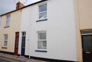 a white building with blue windows on a street at Killick Cottage in Sidmouth