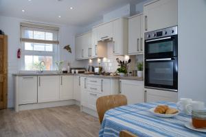 una cocina con armarios blancos y una mesa con un tazón de pan en Waterside, en Sidmouth