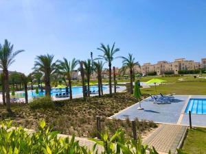 a resort with a swimming pool and palm trees at Chalet ground floor 3BR amwaj sidi abdelrahman in El Alamein