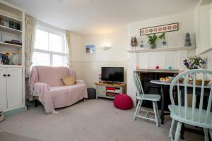 ein Wohnzimmer mit einem rosa Stuhl und einem TV in der Unterkunft Anchor Cottage in Sidmouth
