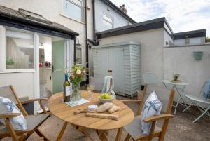 eine kleine Terrasse mit einem Holztisch und Stühlen in der Unterkunft Anchor Cottage in Sidmouth
