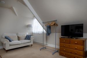 a living room with a couch and a tv on a dresser at Budleigh Breeze in Budleigh Salterton