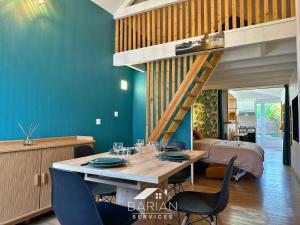 a dining room with a wooden table and a loft bed at 7min de la plage - Maison typique - Cour privative in Fouras