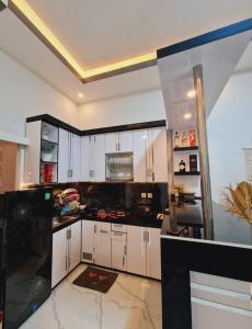 a kitchen with white cabinets and black counter tops at Oemah Sawah99 in Batu