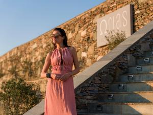 a woman in a pink dress standing in front of a building at Orias Luxury Suites Kythnos in Kithnos