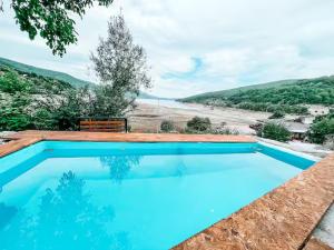 a blue swimming pool with a bench next to a beach at Cece's home in Mavrovo