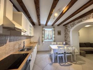 een keuken en eetkamer met een tafel en stoelen bij Apartments Venilia in Lukoran