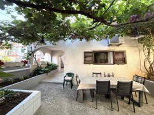 een terras met een tafel en stoelen en een tv aan de muur bij Apartments Venilia in Lukoran