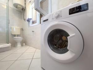 een wasmachine in een badkamer met toilet bij Apartments Venilia in Lukoran