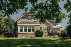 Una casa de ladrillo con una sombrilla en el césped. en NIEUW vanaf juli 2025 Vakantiewoning Borkeldrust, en Rijssen 31 fotos más