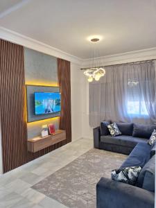 a living room with a blue couch and a tv at Appartement Lazziz in Tangier