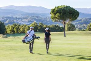 a man and woman walking on a golf course at Villa Blanc Fayence in Tourrettes
