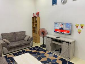 a living room with a couch and a flat screen tv at Homestay Cikgu Ahmed Batu Kikir in Batu Kikir