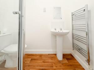 a white bathroom with a sink and a toilet at Euston Road - Beach Apartment 8 in Great Yarmouth +10 photos
