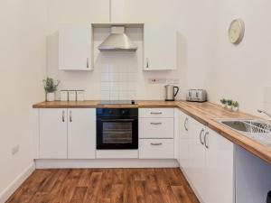 a kitchen with white cabinets and a wooden counter top at Euston Road - Beach Apartment 8 in Great Yarmouth