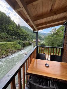 Una mesa en un balcón con vista a un río. en Özden Bungalow, en Çamlıhemşin