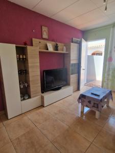 a living room with a flat screen tv and a table at Apartamento Riells in L'Escala