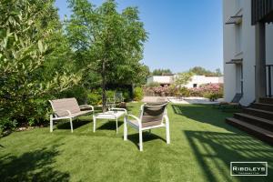 two chairs and a table on a lawn at Superbe T3 climatisé avec WIFI à 400m de la plage in Vias