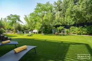 a lawn with chairs and tables in a yard at Superbe T3 climatisé avec WIFI à 400m de la plage in Vias