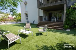 a group of chairs sitting on the grass in front of a house at Superbe T3 climatisé avec WIFI à 400m de la plage in Vias