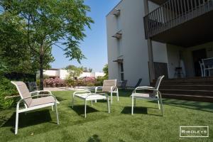 four chairs sitting on the grass in front of a building at Superbe T3 climatisé avec WIFI à 400m de la plage in Vias