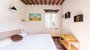 una camera da letto con un letto bianco e una finestra di La finestra sul parco a Lucca