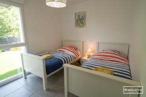 two twin beds in a room with a window at Superbe T3 climatisé avec WIFI à 400m de la plage in Vias