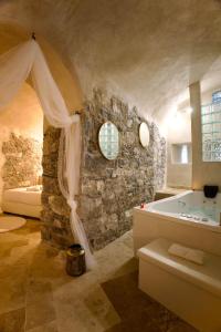 a bathroom with a tub and a stone wall at Love Room du Château Fort - Jacuzzi & Insolite ! in Mercury