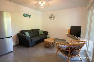 a living room with a couch and a tv at Superbe T3 climatisé avec WIFI à 400m de la plage in Vias