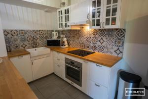 a kitchen with white cabinets and a stove top oven at Superbe T3 climatisé avec WIFI à 400m de la plage in Vias