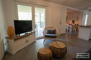 a living room with a flat screen tv sitting on a cabinet at Superbe T3 climatisé avec WIFI à 400m de la plage in Vias