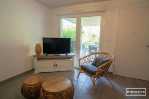 a living room with a tv and a chair and a table at Superbe T3 climatisé avec WIFI à 400m de la plage in Vias