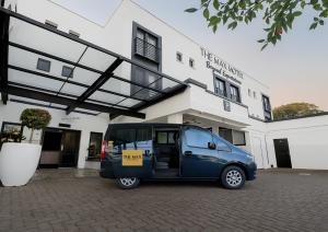 a small blue van parked in front of a building at The Max Hotel Sandton in Johannesburg
