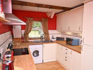 eine Küche mit weißen Schränken und einer Waschmaschine in der Unterkunft Petty Knowes Cottage in Newcastle upon Tyne