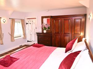 ein Schlafzimmer mit einem großen Bett mit roten Kissen in der Unterkunft Petty Knowes Cottage in Newcastle upon Tyne