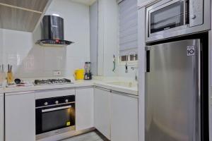 a kitchen with white cabinets and a stainless steel refrigerator at Stay Well Homes Comfortinn in Eregun +8 photos