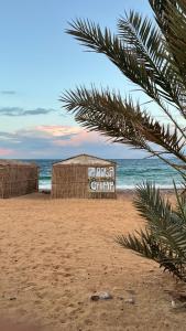 a sign on a beach with the ocean in the background at Zoola beach camp & Eco lodge in Nuweiba