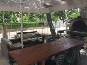 un tavolo in legno e sedie sotto un ombrellone di Under the Fig tree a Pirovac (Slosella)