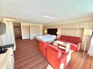 a hotel room with a bed and a red couch at Schwarzwalapartment Nr 6 Presidential Suite 40qm Doppelbett Modern in Altensteig