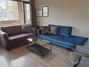 Una sala de estar con un sofá azul y una mesa. en Appartment Bella - 2 minutes from the beach, en Noordwijk aan Zee