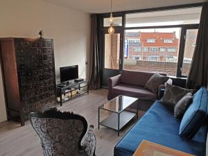 Una sala de estar con un sofá azul y un televisor en Appartment Bella - 2 minutes from the beach, en Noordwijk aan Zee