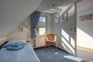 ein Schlafzimmer mit einem Bett und einem Stuhl und einem Fenster in der Unterkunft Landhaus am Ufer - Wohnung 4 in Heiligenhafen