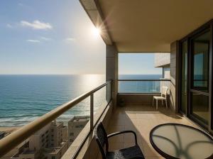 内坦亚Apartment in Netanya的带桌椅和海景的阳台