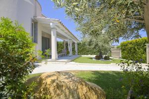 una casa bianca con una roccia nel cortile di Villa Rei M&M- sea view, swimming pool & Jacuzzi a Costa Rei