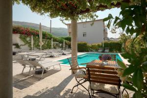a swimming pool with chairs and a table and a house at Olive Tree apartments in Podstrana
