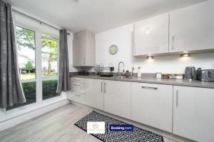 a kitchen with white cabinets and a large window at 3 Bedroom House By The Yuma Homes Short Lets & Serviced Accommodation In Kent With Wifi & Parking in Ashford