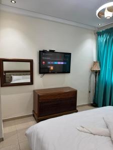 een slaapkamer met een flatscreen-tv aan de muur bij Sweet Home Agadir Appartement moderne avec piscine et commerces à pied in Agadir +23 foto's