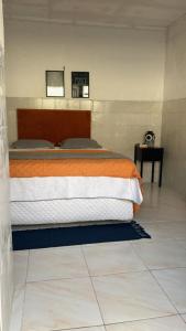 a bedroom with a bed with an orange and white blanket at Kitnet 17a in São Luís