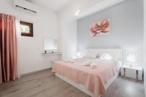 a white bedroom with a bed with a pink blanket at Cozy Guesthouse in Koskinou