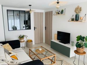 a living room with a couch and a tv at Logement cosy en centre ville in Talmont